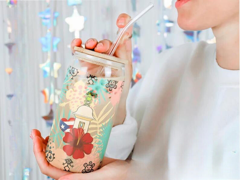 Woman enjoying a drink from a 16oz frosted Libbey glass adorned with Puerto Rican flag, hibiscus flower, and cultural symbols, capturing the island's essence.